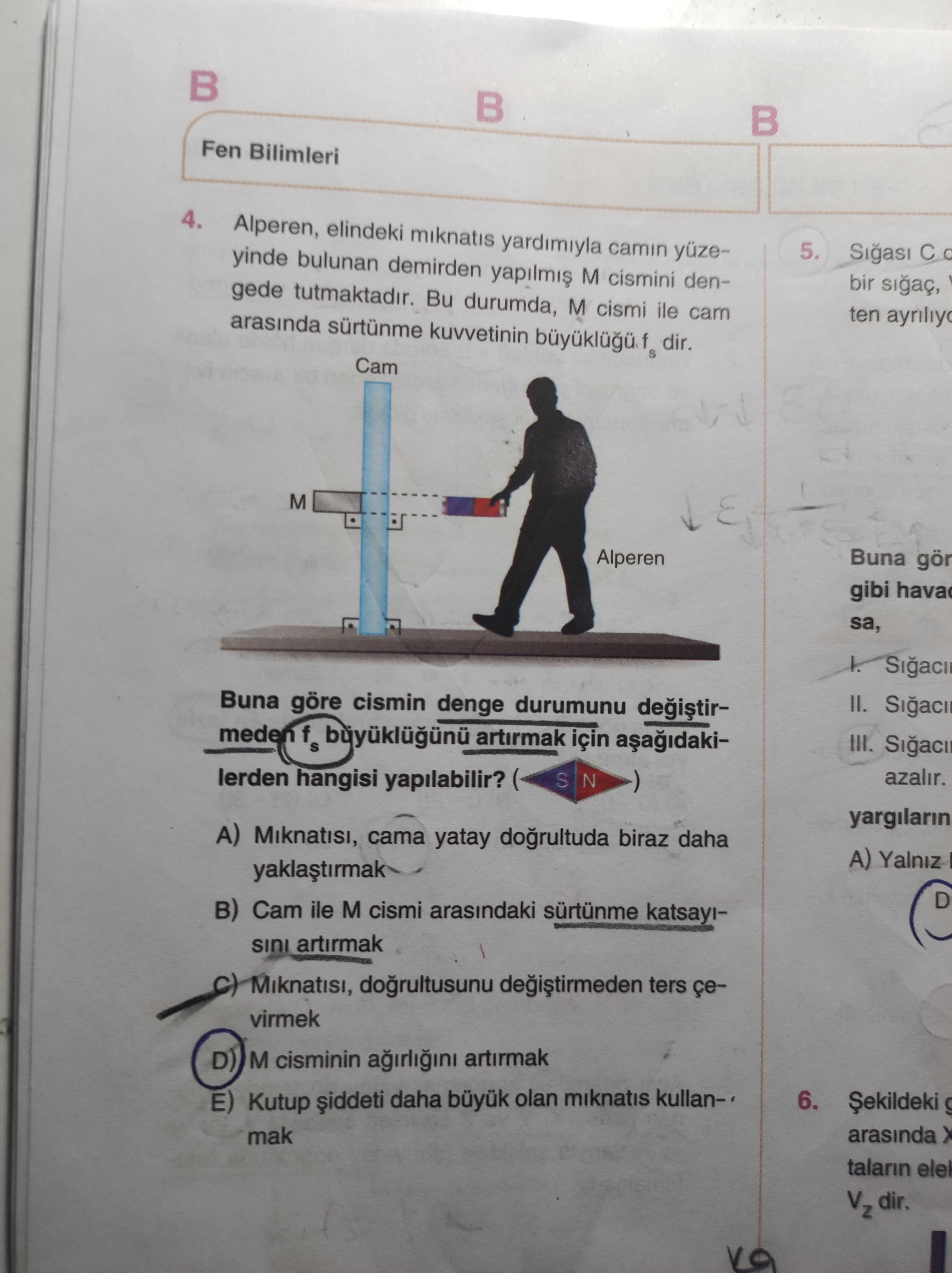 Alperen, elindeki mıknatıs yardımıyla camın yüzeyinde bulunan demirden yapılmış M cismini dengede