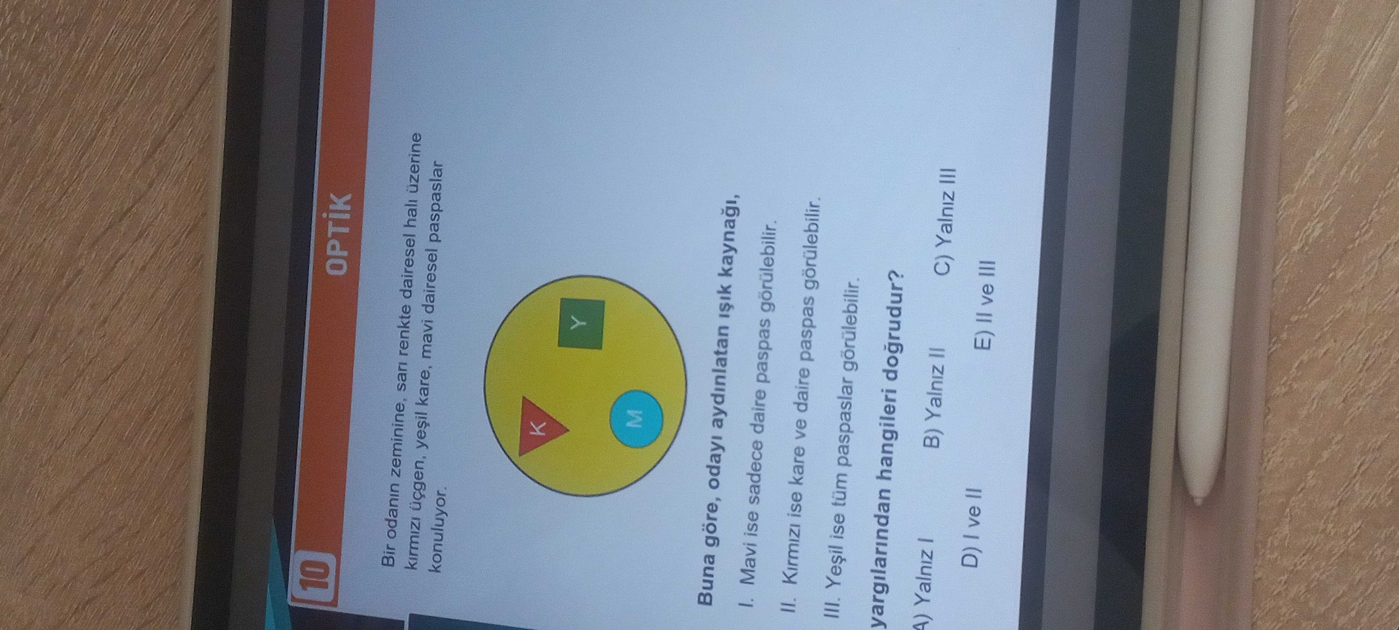 Bir odanın zeminine, sarı renkte dairesel halı üzerine kırmızı üçgen, yeşil kare, mavi daire, mavi